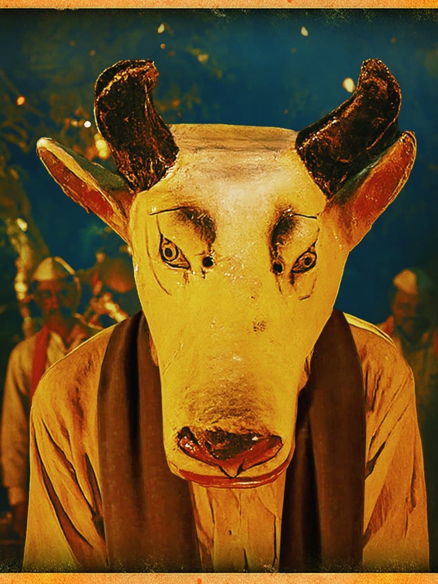 Gondhal key art, portrait crop: a masked Gondhali performer in a painted bull mask lit by firelight.